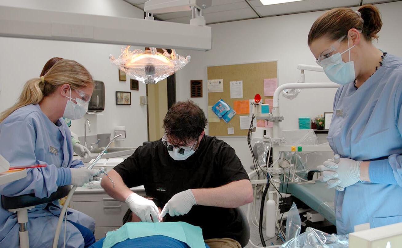 三个学生在病人身上练习牙科手术